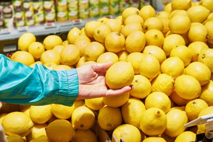 Hand Picking Lemon From Pile In Store