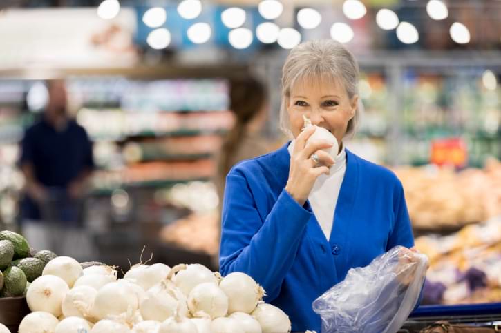 Woman Smelling Onion In Store