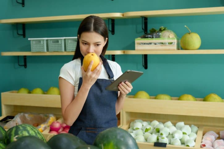 Woman Smelling Mango in Market