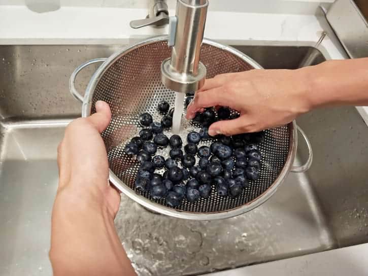 Rinsing Blueberries Under Running Water